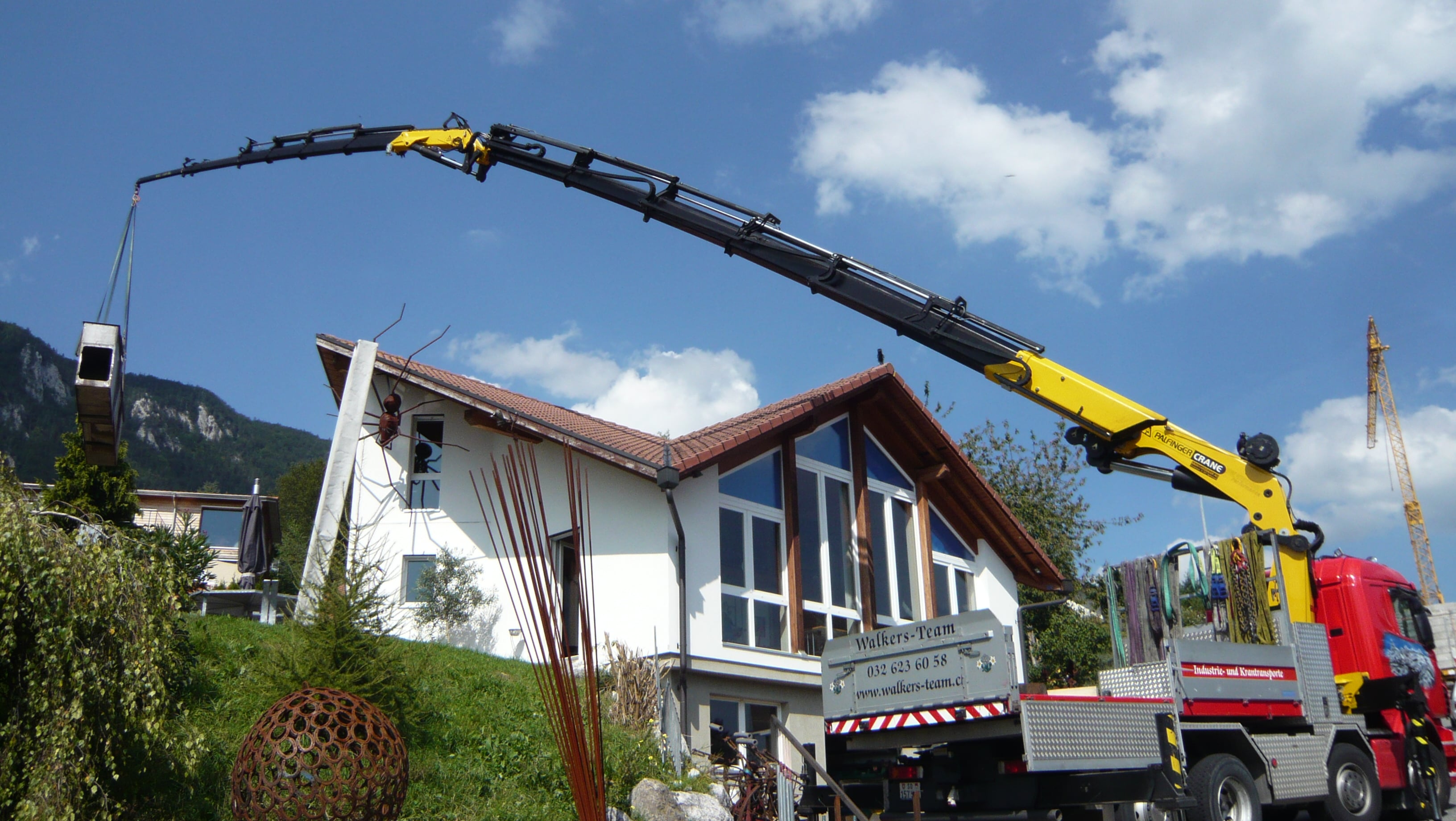 Walker's Team yellow crane in operation lifting building materials - professional crane transport service