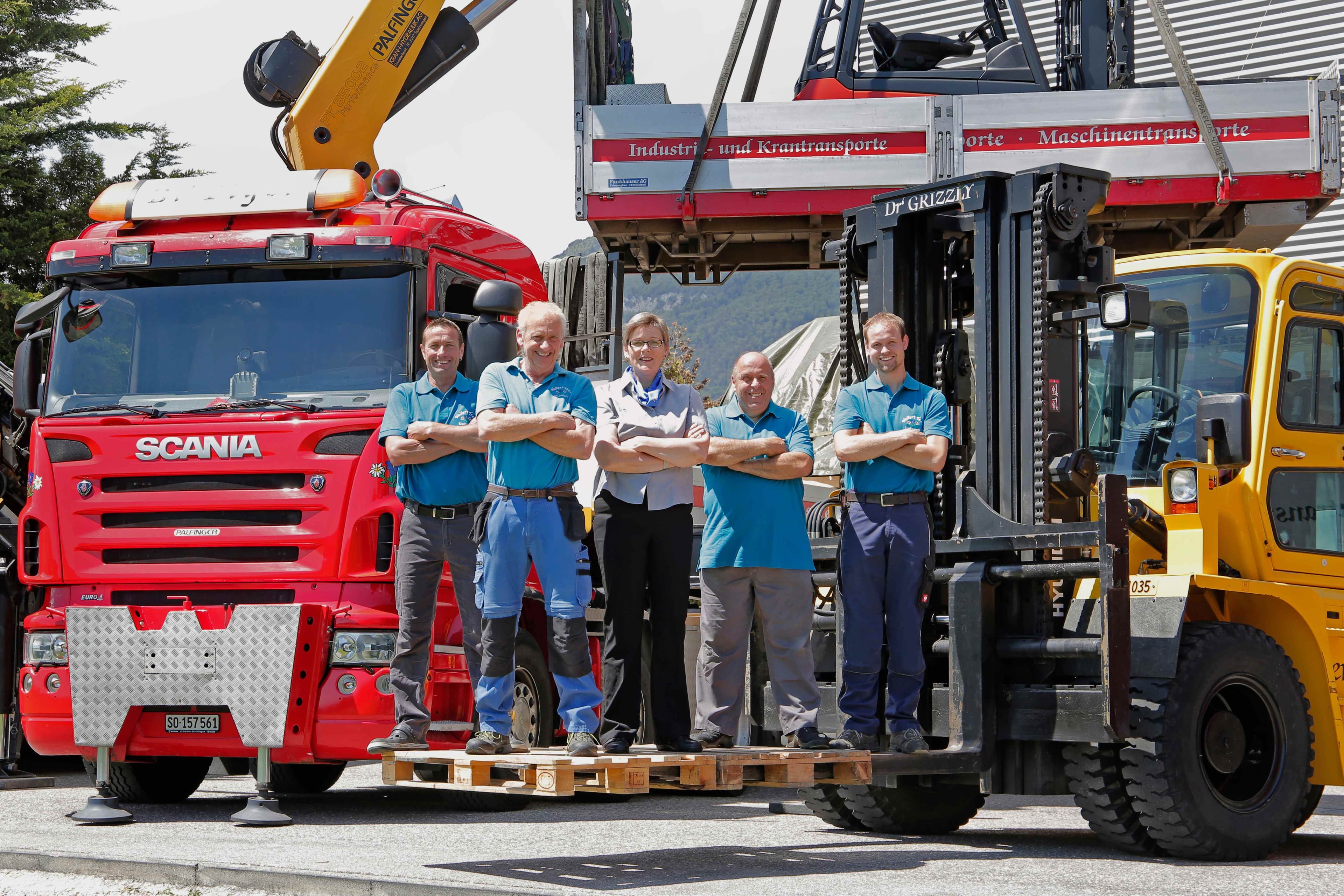 Walker's Team staff in blue uniforms standing in front of red Scania truck with crane equipment